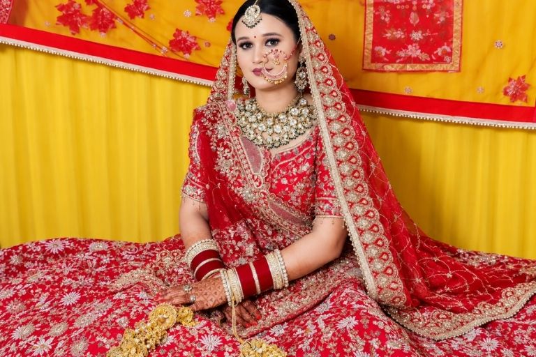 Bridal wear model in red embroidered wedding lehenga.